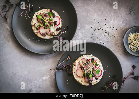 Healthy sandwiches with curd cheese, radishes and micro greens (sprouts) on a dark background, flatlay Stock Photo