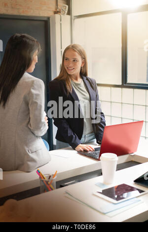 Two female coworkers discussing presentation ideas in modern office Stock Photo