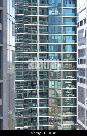 Glass exterior wall of tall apartment building with rows and columns of balconies and windows.