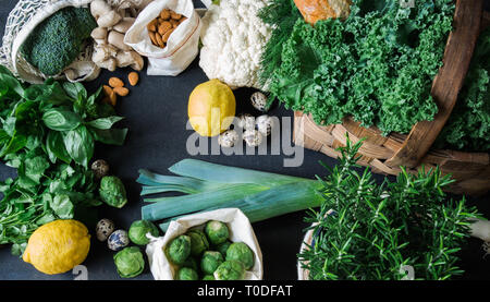 Healthy vegetarian ingredients for cooking. Various clean vegetables, herbs, nut and bread on black background. Products from the market without plast Stock Photo