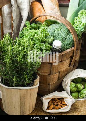 Healthy vegetarian ingredients for cooking. Various clean vegetables, herbs, nut and bread in basket on wooden chair. Products from the market without Stock Photo