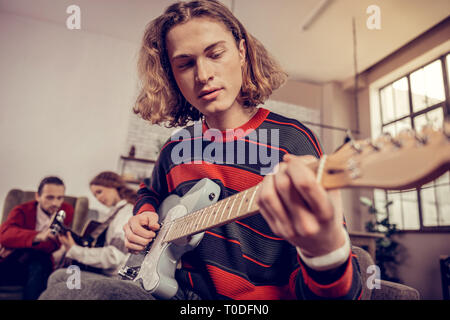 Music student wearing red and blue sweater playing the guitar Stock Photo