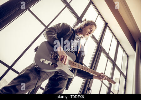 Musician wearing jeans and black leather jacket playing the guitar Stock Photo