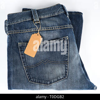 folded blue jeans and tied brown blank tag on white background, top view Stock Photo