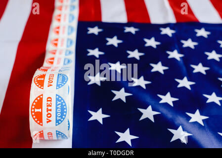 I vote today stickers roll, in US elections on American flag. Stock Photo