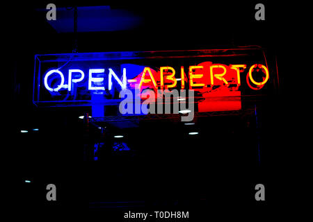 Neon shop "Open" (In Spanish and English) store sign at night in street with copy space Stock Photo