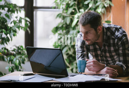 Young business man work on computer in his pleasant studio home office. Freelance professions in cool workplace environment: programmer, designer, arc Stock Photo