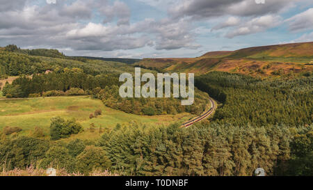 Near Levisham, North Yorkshire, England, UK: September 13, 2018: A train of the historic North Yorkshire Moors Railway passing Newtondale, seen from S Stock Photo