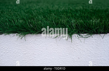 Close up image of green artificial turf on top of a white wall Stock Photo