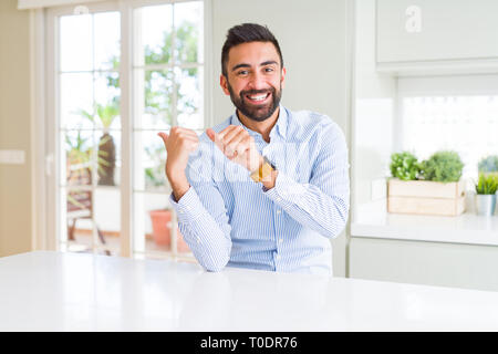 Handsome hispanic business man Pointing to the back behind with hand and thumbs up, smiling confident Stock Photo