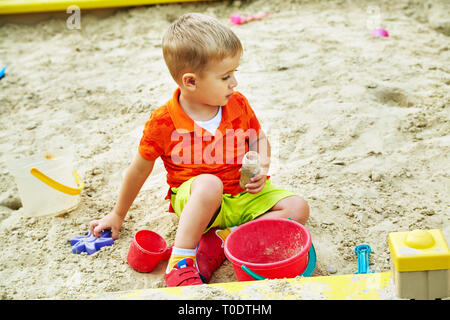 funny little boy on playground. playing child in sandbox Stock Photo