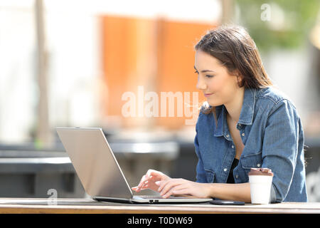 Serious woman using a laptop on a table sitting in a park Stock Photo