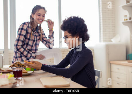 Positive delighted teenager spending free time in kitchen Stock Photo