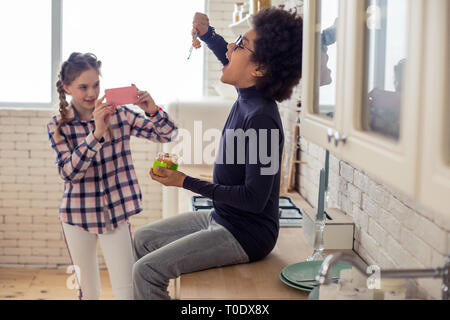 Cute longhaired kid using her telephone during game Stock Photo