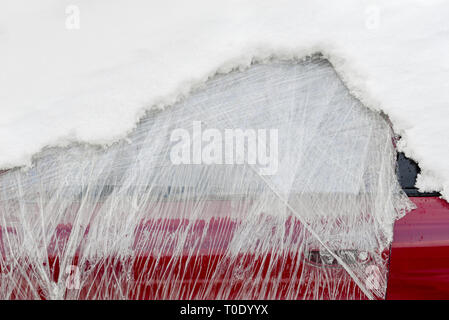 Front window of abandoned car wrapped in plastic and covered with snow Stock Photo