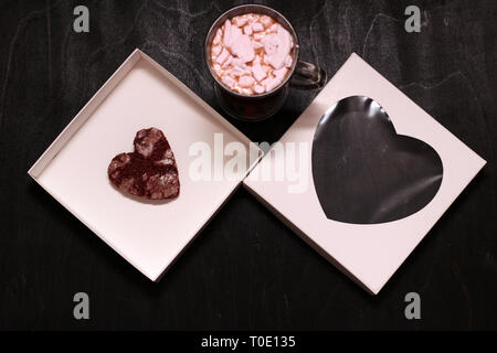hot drink in a glass cup with pink marshmallows and white box with a transparent cover in the form of heart with cookies Stock Photo