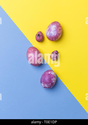 Pink Easter eggs on yellow and blue background. Concept of office Easter. Flat lay, top view, free space for text Stock Photo