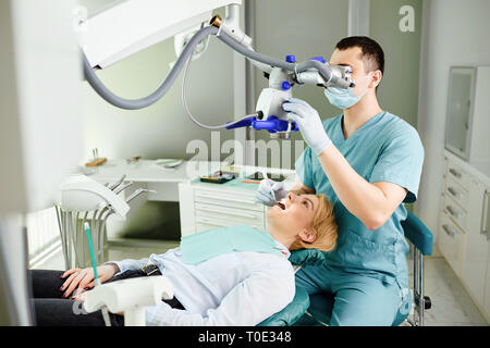 Male dentist looking through a microscope Stock Photo