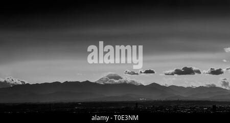 Iconic Mount Fuji wrapped in clouds like and old painting, seen from Tokyo in Japan (Black and White) Stock Photo