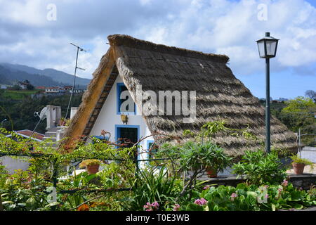 Typical stone houses, painted red, white and blue, with triangular shaped straw thatched roof in the village of Santana / Santa Ana, Madeira, Portugal Stock Photo