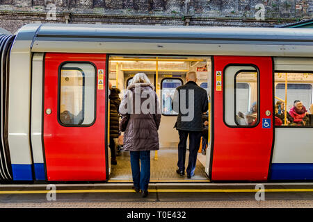 People boarding a District Line train at Sloane Square Underground station, London, UK Stock Photo