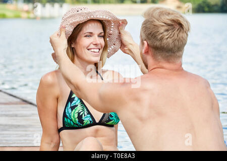 Young man is putting a big summer hat on his head Stock Photo