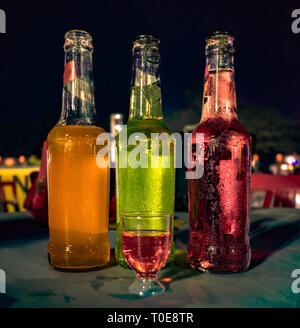 Three bottles of different colored Wines placed adjacent to each other with a small glass filled with red wine for tasting at a Wine Tasting Festival. Stock Photo
