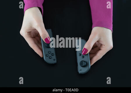 HEGGENES - FEBRUARY 14: Top view of woman hands holding Nintendo Switch gaming controllers for playing digital video games isolated on black Stock Photo