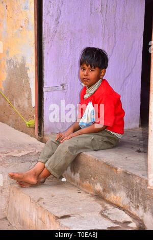 Indian Boy sitting on step in red jumper, Bundi, Rajasthan, India Stock Photo