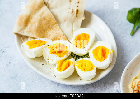 Boiled eggs cutted in halfs seasoned with pepper and salt with pita bread on a plate, healthy appetizers meal Stock Photo