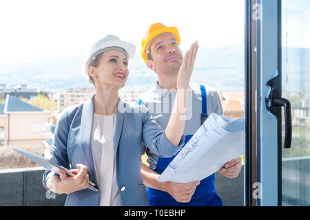 Architect and construction worker checking windows on site Stock Photo