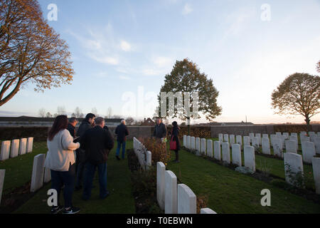 A tour guide shows tourists the graves of fallen soldiers of the first world war as they walk amidst headstones in a graveyard in France. Stock Photo