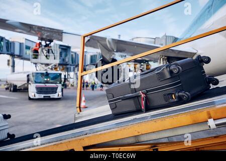 Preparations before flight. Loading luggage into airplane against refueling of airplane at airport. Travel and industry concepts. Stock Photo