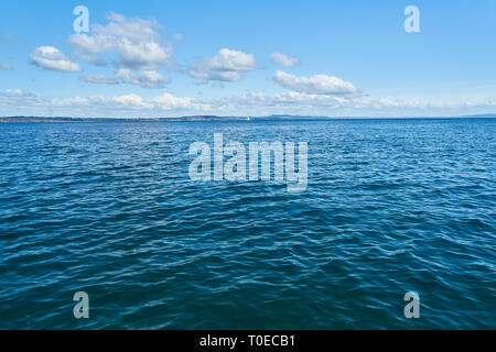 Gentle ripples on water from the Atlantic Ocean in front of a blue sky Stock Photo