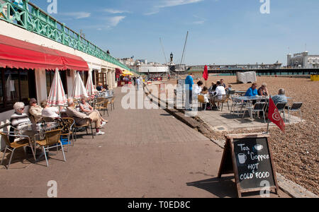 Holidaymakers enjoying refreshments sitting outside a cafe on the seafront in Brighton, Sussex, England. Stock Photo