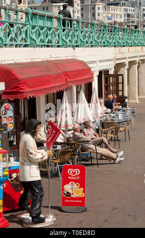 Holidaymakers enjoying refreshments sitting outside a cafe on the seafront in Brighton, Sussex, England. Stock Photo