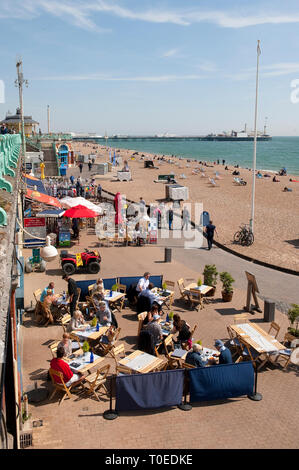 People sitting outside cafes on the promenade on the seafront in Brighton, Sussex, England. Stock Photo