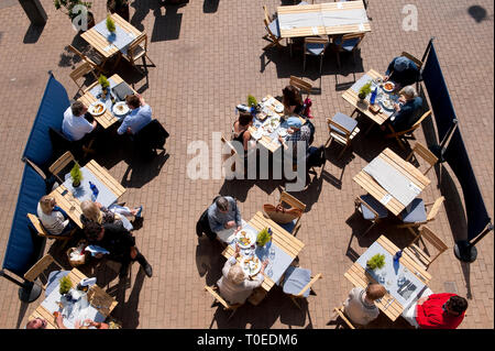 People sitting outside cafes on the promenade on the seafront in Brighton, Sussex, England. Stock Photo