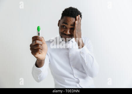 Young unhappy african american man looking at pregnancy test. Handsome sad man frustrated and having problems. Guy depressed because of result of pregnancy test Stock Photo