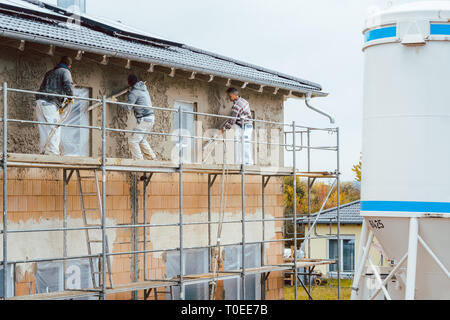 Plaster worker on scaffold working Stock Photo