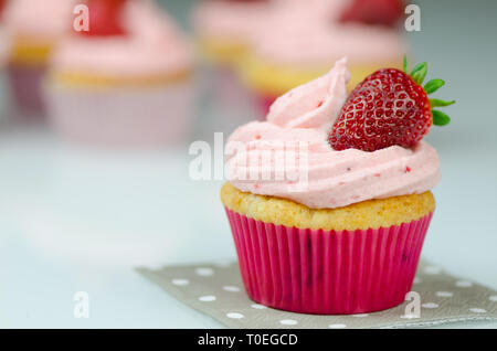 Delicious pink strawberry cupcake with a strawberry. Cupcakes and pink icing with a strawberries on top Stock Photo