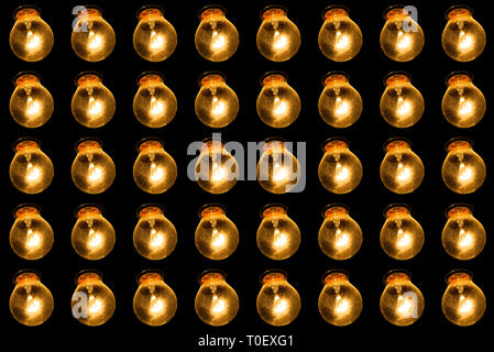 Glowing lamps on a black background. Many lamps in a row shine with yellow light. Loft concept Stock Photo