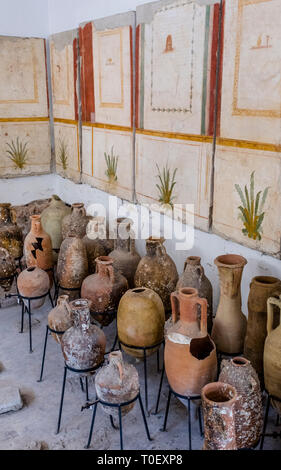 Urns, vases and other pottery displayed beneath fragments of painted walls from ancient Roman ruins, at the Villa Romana museum in Minori, Italy Stock Photo