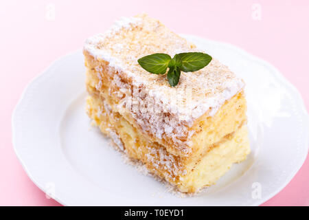 French Mille feuille cake with vanilla cream decorated with mint on a pink background Stock Photo