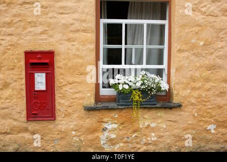 Traditional Red Post Box set into a stone cottage wall in a village in Wales Stock Photo