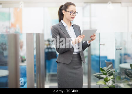 Portrait of beautiful young businesswoman using digital tablet standing in office, copy space Stock Photo