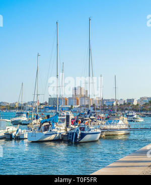 Yachts and motor boats moored in marina of Portimao, people walking at embankment in warm evening sunlight, Portugal, Europe Stock Photo