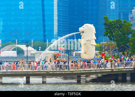 SINGAPORE - JANUARY 14, 2017: Crowd of tourists by Singapore Lion fountain, glass facades of skyscrapers in background Stock Photo