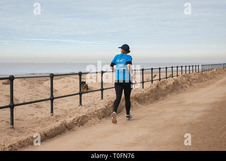 Woman running on the seafront promenade at Crosby, Merseyside. 20th March, 2019. Warm hazy spring day at the coast. Credit: MWI/AlamyLiveNews Stock Photo