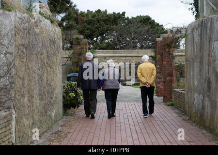 Elderly people walking into the entrance of a public garden, two of which are holding hands Stock Photo